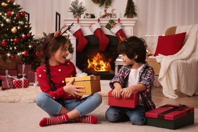 Photo of Happy children with Christmas gift boxes on floor at home