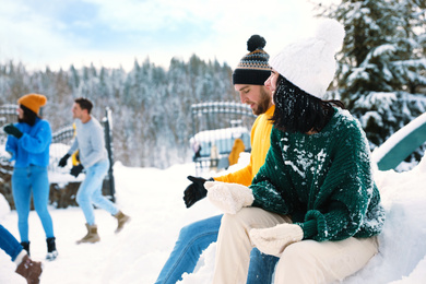 Photo of Group of friends playing snowballs outdoors. Winter vacation