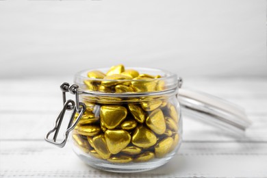 Jar with delicious heart shaped candies on white table