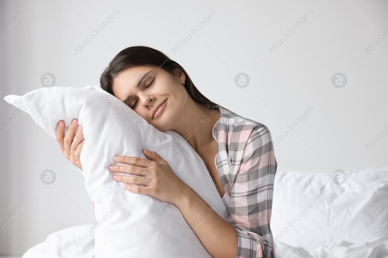 Photo of Beautiful young woman hugging pillow on bed at home