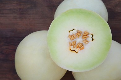 Photo of Whole and cut fresh ripe melons on wooden table, top view