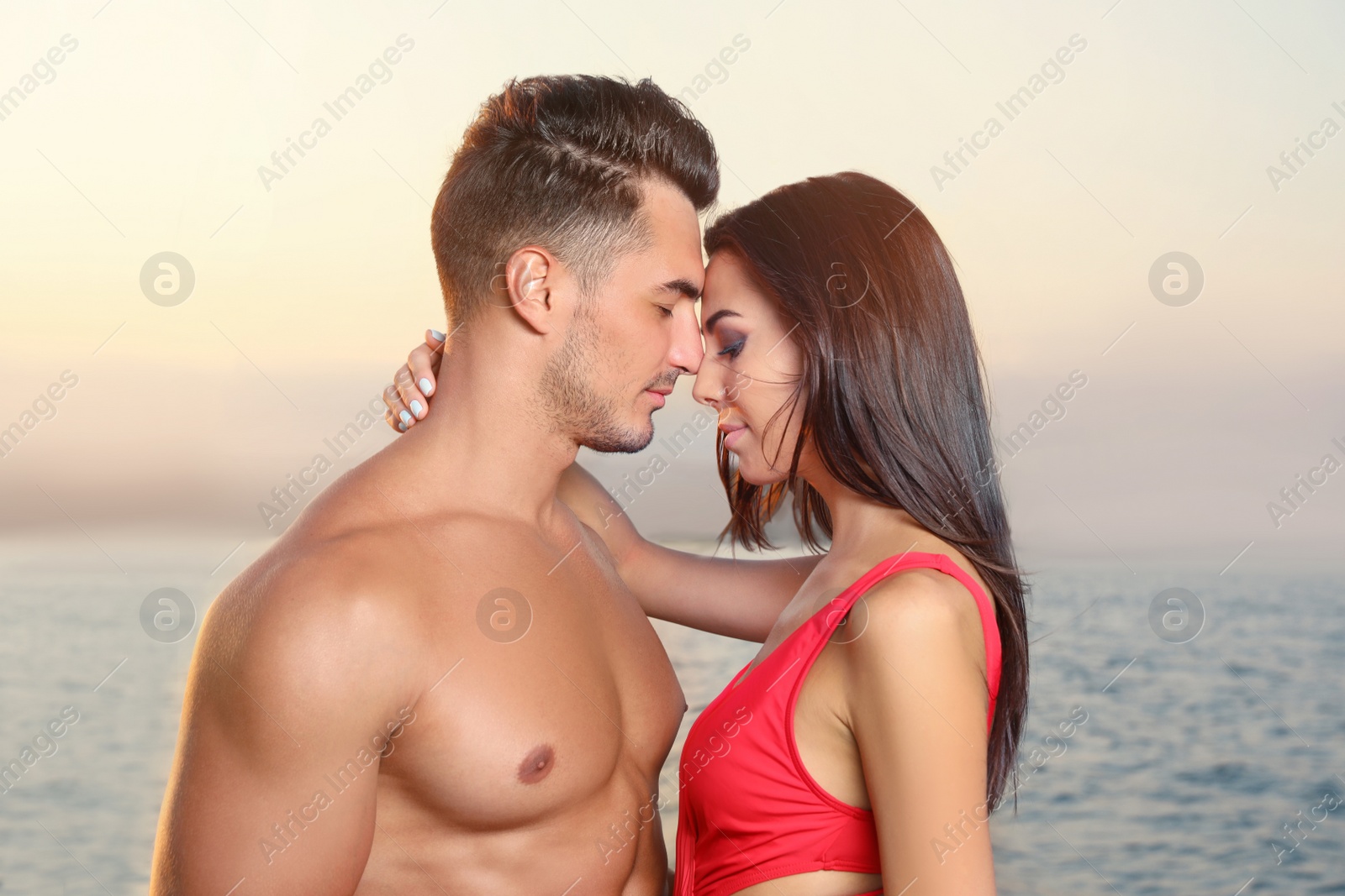 Photo of Young man and his beautiful girlfriend in bikini on yacht. Happy couple during sea trip