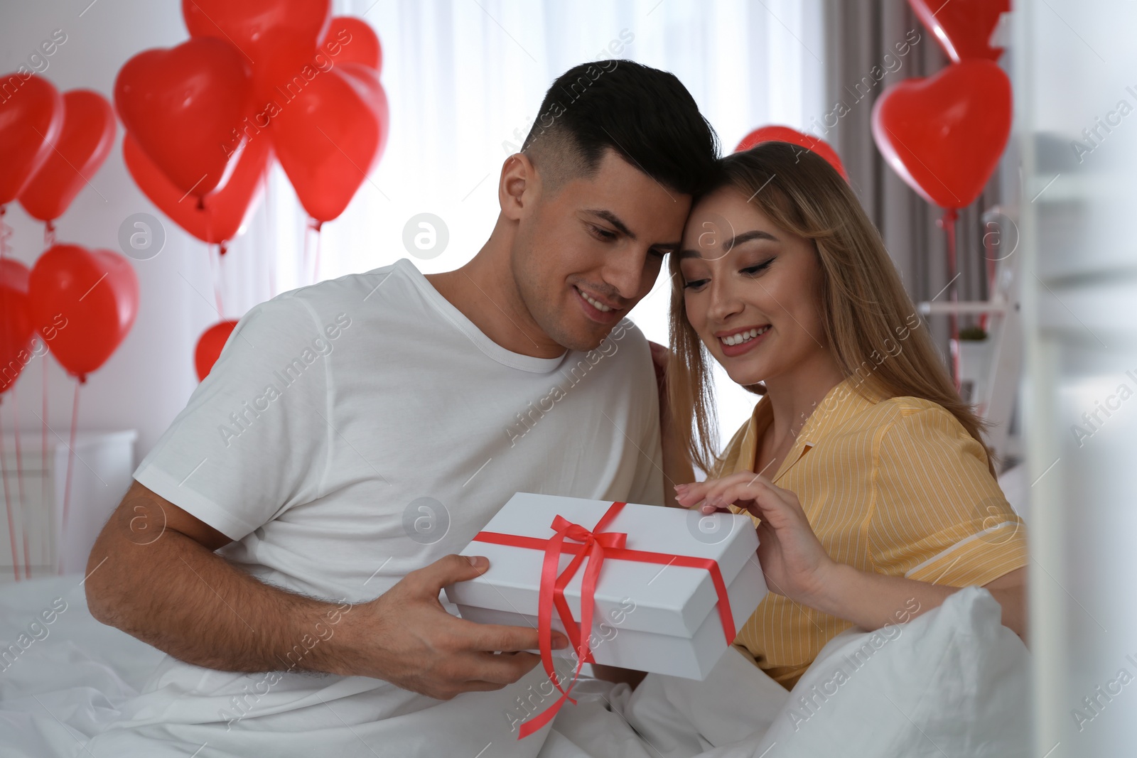 Photo of Lovely couple with gift in room. Valentine's day celebration