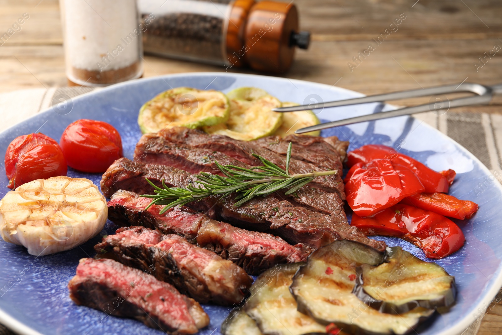 Photo of Delicious grilled beef steak with vegetables and spices on table, closeup