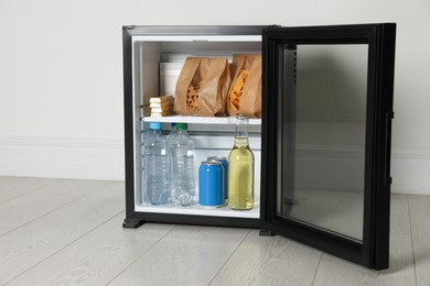 Photo of Mini bar filled with food and drinks near white wall indoors