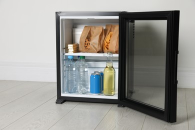 Mini bar filled with food and drinks near white wall indoors