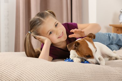 Cute girl with her playful dog on bed at home. Adorable pet