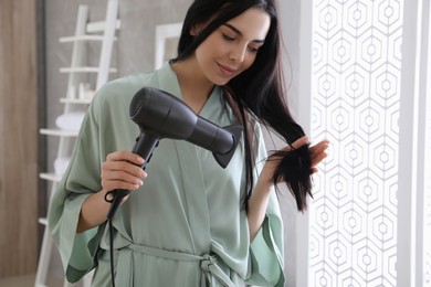 Photo of Beautiful young woman using hair dryer in bathroom