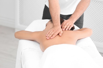 Photo of Relaxed woman receiving back massage in wellness center