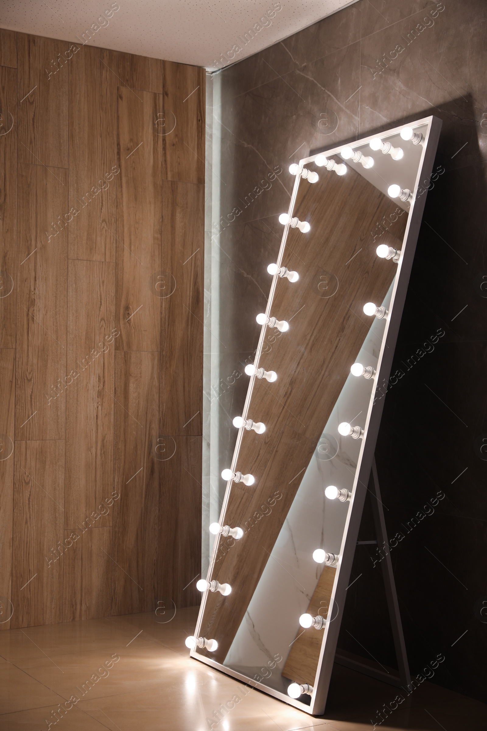 Photo of Modern mirror with light bulbs near brown wall in room