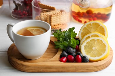 Photo of Cup with delicious immunity boosting tea and ingredients on white wooden table
