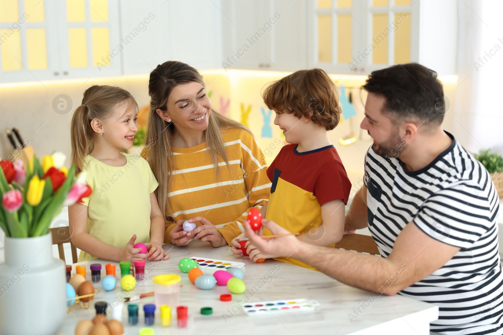 Photo of Happy Easter. Cute family with painted eggs at white marble table in kitchen