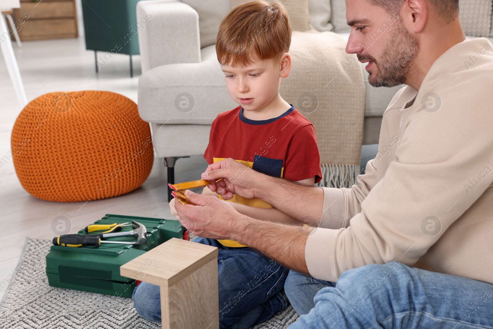 Photo of Father and son measuring shelf together at home. Repair work