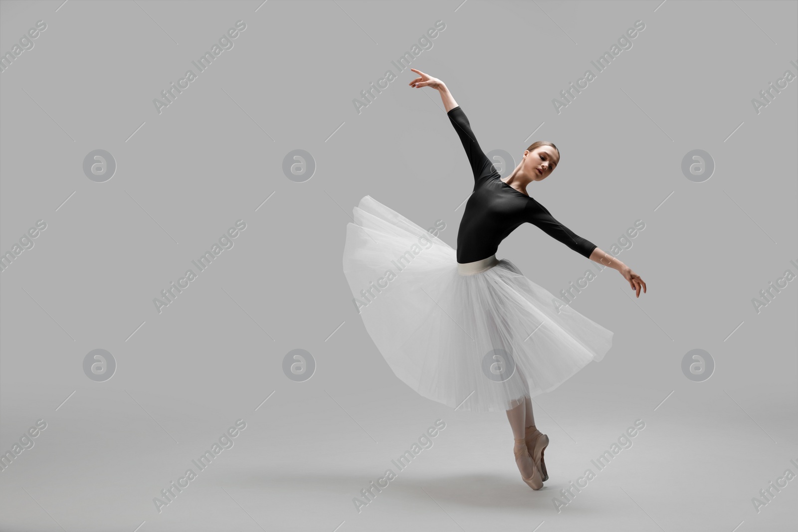 Photo of Young ballerina practicing dance moves on light grey background. Space for text