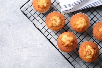 Photo of Delicious sweet muffins on light grey textured table, top view. Space for text