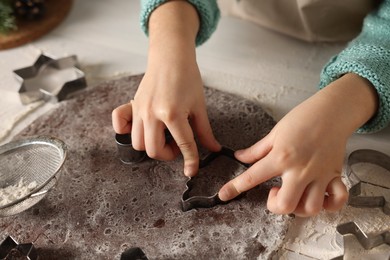 Photo of Little child making cookies at white wooden table, closeup