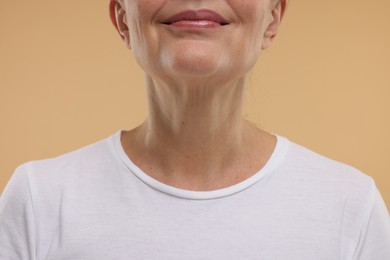 Mature woman with healthy skin on beige background, closeup