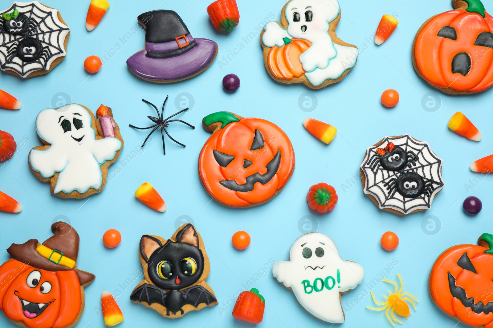 Photo of Tasty cookies and sweets for Halloween party on light blue background, flat lay