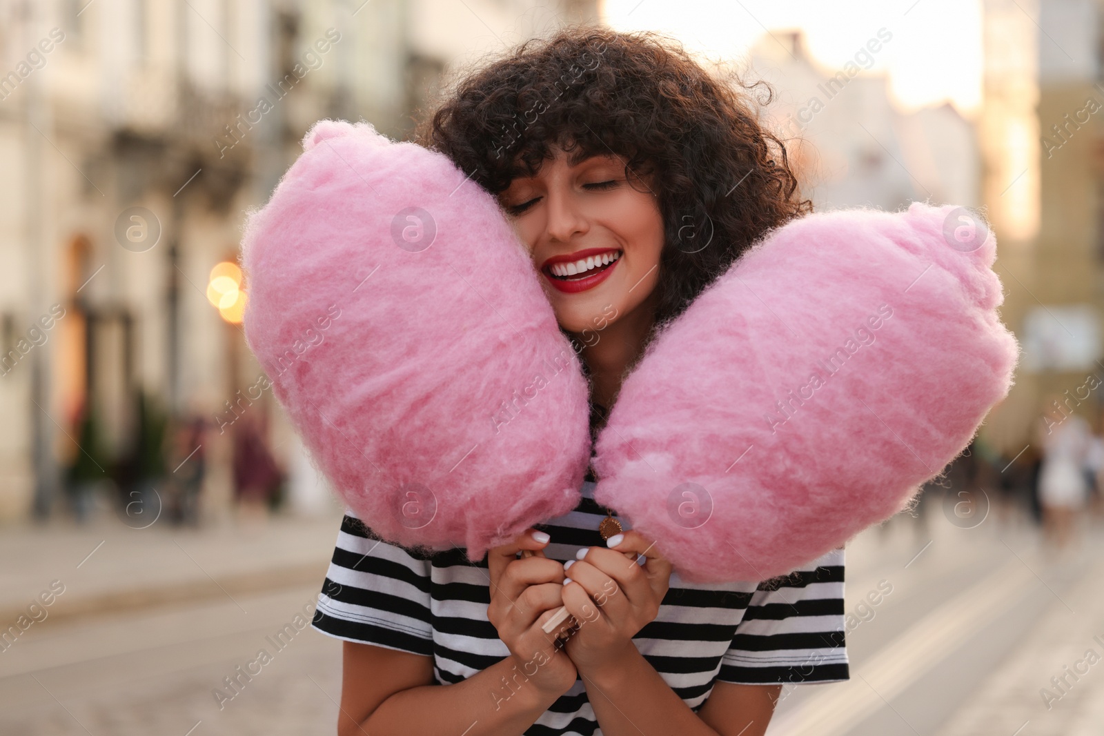 Photo of Portrait of happy woman with pink cotton candies on city street