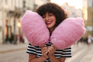 Photo of Portrait of happy woman with pink cotton candies on city street