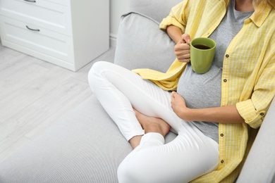 Beautiful pregnant woman drinking tea at home, closeup