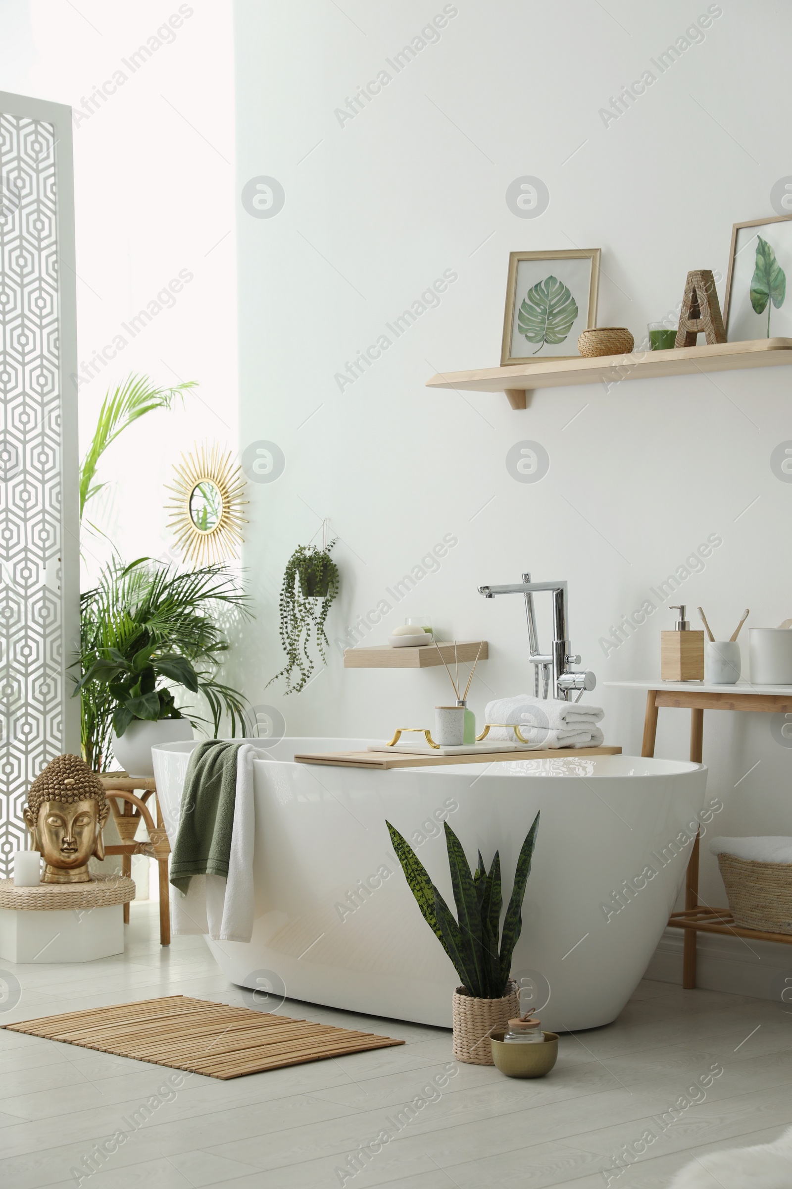 Photo of Stylish bathroom interior with modern tub, houseplants and beautiful decor. Home design