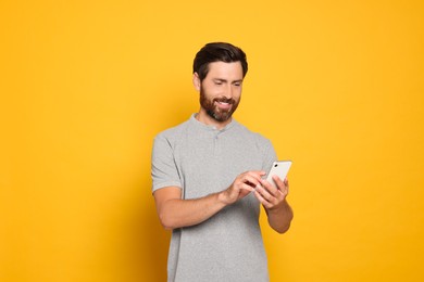 Photo of Happy man with smartphone on yellow background