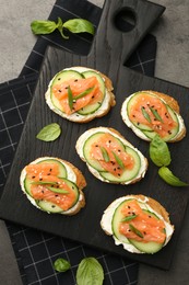 Photo of Tasty canapes with salmon, cucumber and cream cheese on grey table, top view