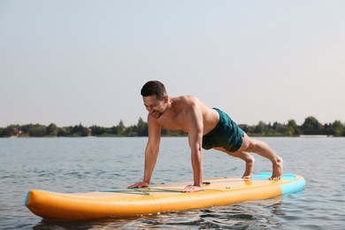 Photo of Man practicing yoga on SUP board on river