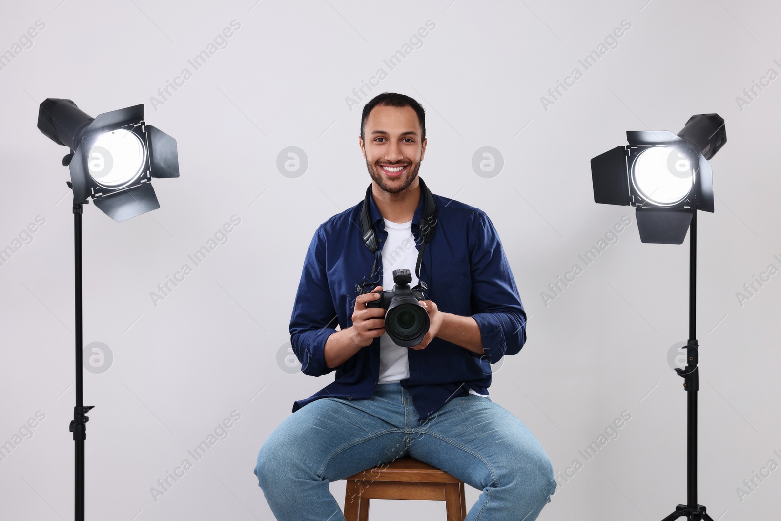 Photo of Young professional photographer with camera in modern photo studio