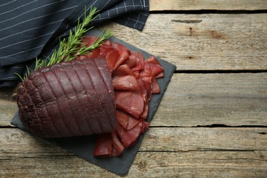 Photo of Tasty bresaola and rosemary on wooden table, top view. Space for text