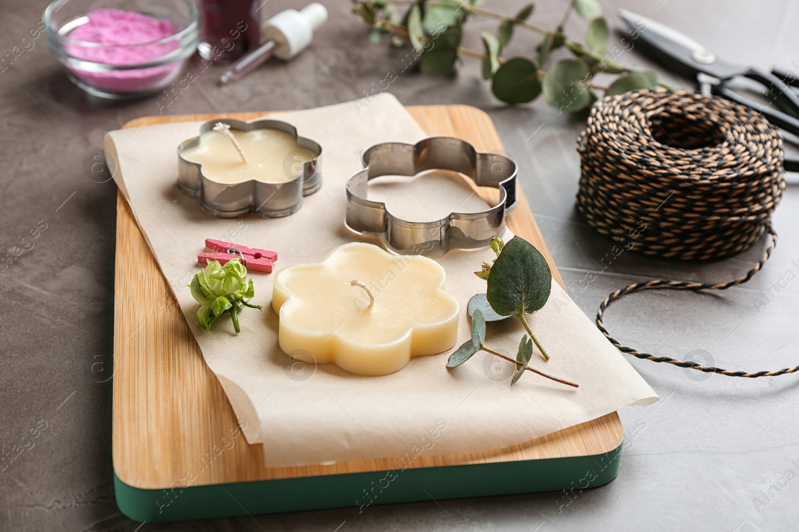 Photo of Handmade candles with cutters on stone background