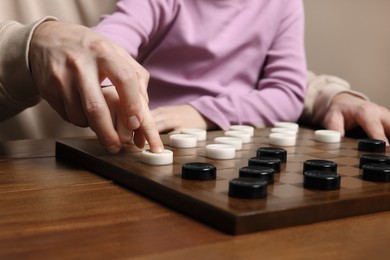 Photo of Playing checkers. Father learning his daughter at wooden table, closeup