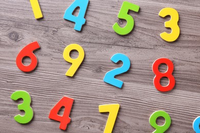 Photo of Colorful numbers on wooden school desk, flat lay