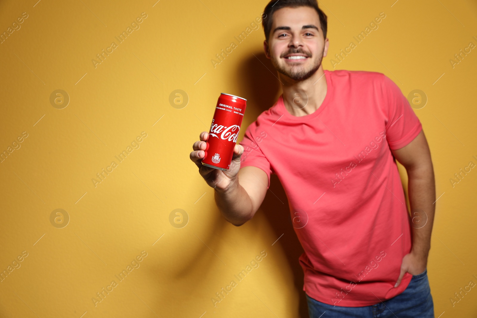 Photo of MYKOLAIV, UKRAINE - NOVEMBER 28, 2018: Young man with Coca-Cola can on color background, space for text