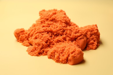 Photo of Pile of orange kinetic sand on beige background, closeup