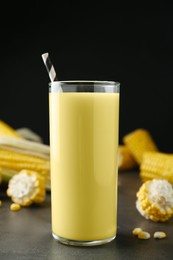 Photo of Freshly made corn juice in glass on grey table against black background