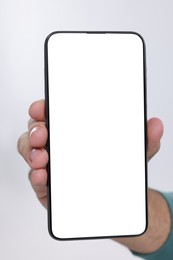 Man holding smartphone with blank screen on white background, closeup