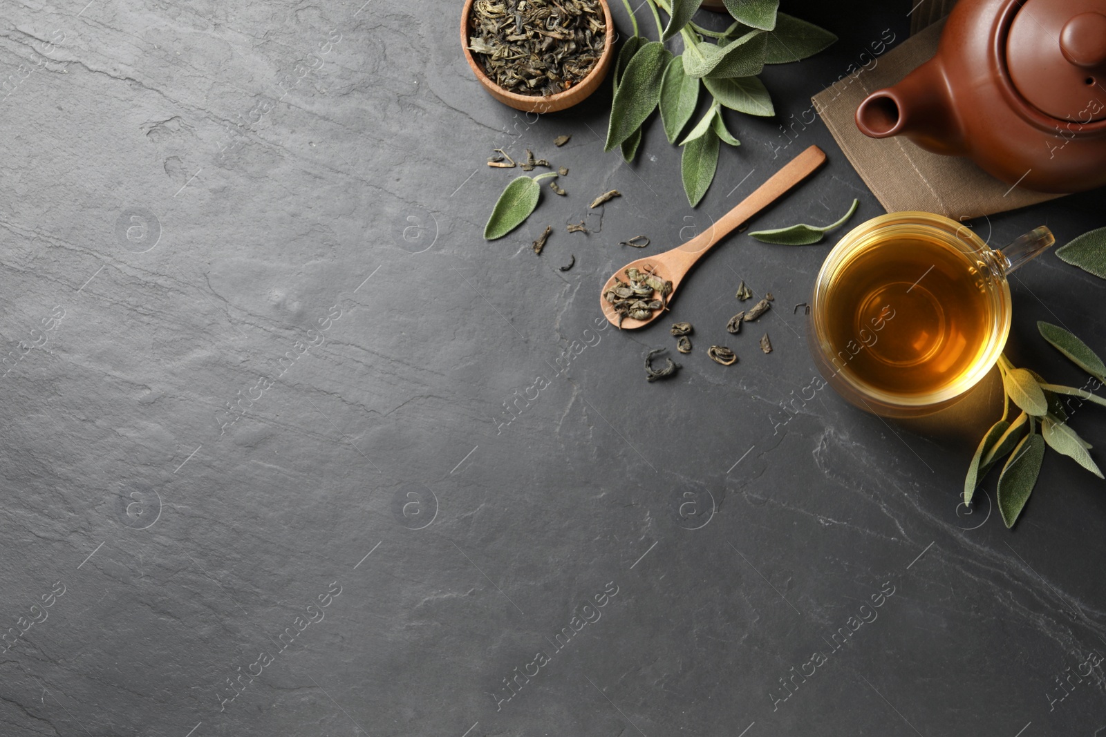 Photo of Flat lay composition with aromatic sage tea on black table. Space for text