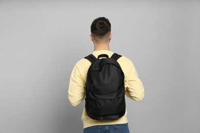Photo of Young man with stylish backpack on light grey background, back view