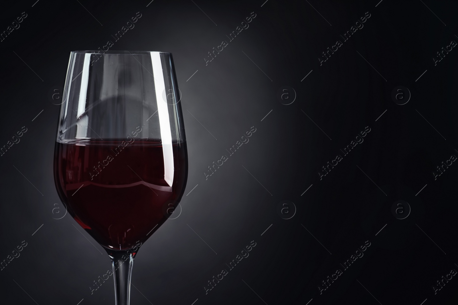 Photo of Glass with delicious red wine on dark background