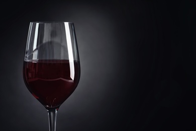 Photo of Glass with delicious red wine on dark background