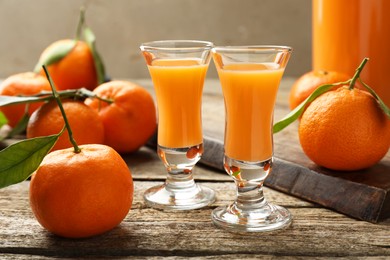 Photo of Delicious tangerine liqueur and fresh fruits on wooden table