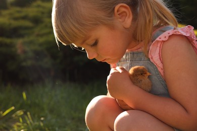 Photo of Little girl with cute chick outdoors. Baby animal