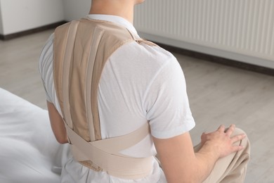 Closeup view of man with orthopedic corset sitting in room