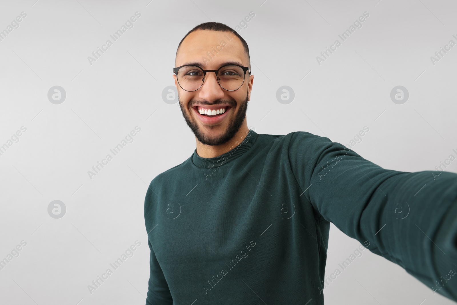 Photo of Smiling young man taking selfie on grey background