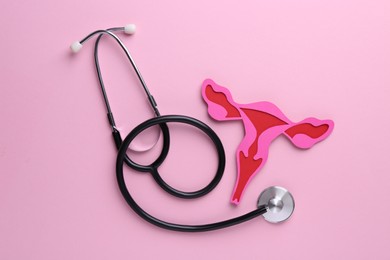 Photo of Reproductive medicine. Paper uterus and stethoscope on pink background, top view