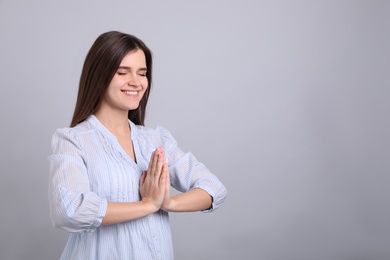 Photo of Young woman meditating on grey background, space for text. Stress relief exercise