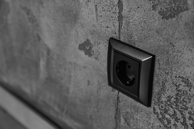 Closeup view of modern power socket on grey wall, space for text. Electrical supply