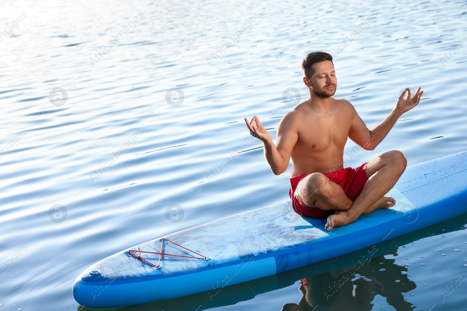 Photo of Man meditating on light blue SUP board on river